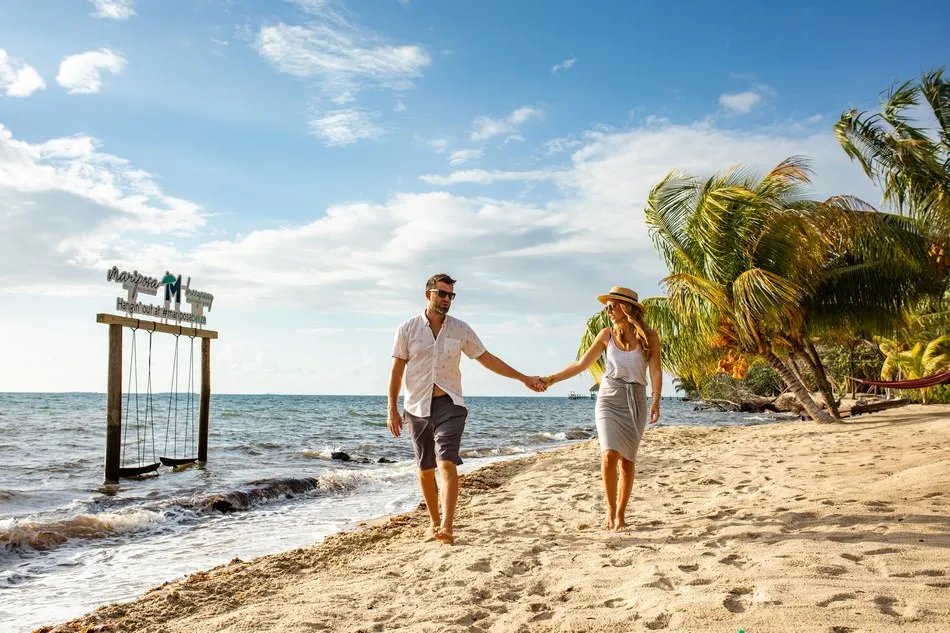 A couple on a beach swing over the water