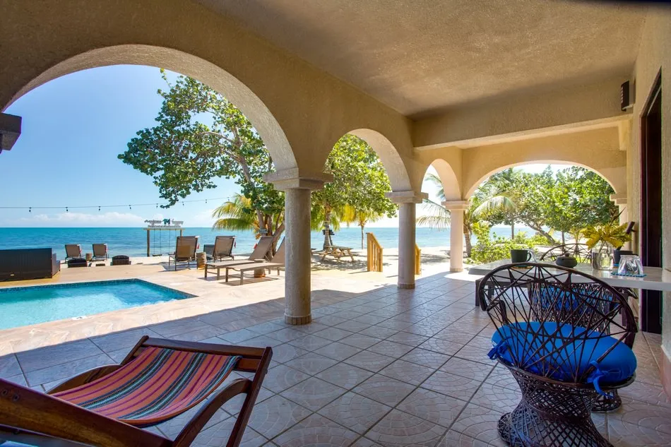 An oceanfront suite patio with hammock and pool beyond