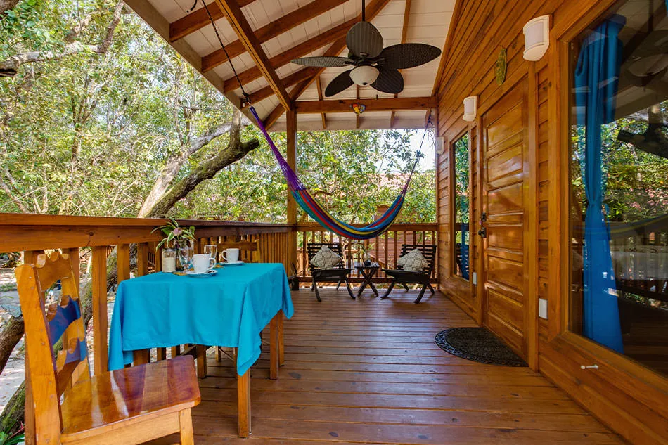 A garden treehouse porch with hammock among tropical greenery